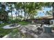 Lush backyard with a stone patio, fire pit, mature trees providing shade, and space for outdoor seating at 2817 Rustic Oaks Dr, Palm Harbor, FL 34684