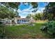 Lush backyard featuring a patio, outdoor dining set, swing set, fire pit, mature trees offering shade, and landscaping at 2817 Rustic Oaks Dr, Palm Harbor, FL 34684