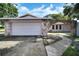 Charming home featuring a stone archway and a two-car garage with a white door, enhancing its curb appeal at 2817 Rustic Oaks Dr, Palm Harbor, FL 34684