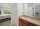 Bathroom with wood cabinets, neutral counters, and a view into the bedroom at 30352 Elderwood Dr, Wesley Chapel, FL 33543