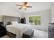 Inviting bedroom featuring a ceiling fan, headboard, and a large window with neighborhood views at 30352 Elderwood Dr, Wesley Chapel, FL 33543