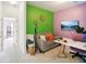 Living room with green and pink accent walls, sofa, TV, and study area at 30352 Elderwood Dr, Wesley Chapel, FL 33543