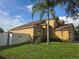 Beautiful home exterior with well-maintained lawn, palm tree, stone accents, and white fence at 31141 Harthorn Ct, Wesley Chapel, FL 33543