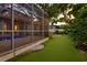 View of a screened-in pool and putting green in the backyard with beautiful landscaping at 3307 W Knights Ave, Tampa, FL 33611