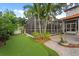 Private backyard featuring a screened lanai, mature palm trees, and artificial turf at 3307 W Knights Ave, Tampa, FL 33611