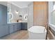 Bathroom featuring double sinks, soaking tub, blue cabinets, vanity lights, and hardwood floors at 3307 W Knights Ave, Tampa, FL 33611