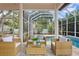 Covered patio with wicker furniture overlooks a beautiful screened-in pool at 3307 W Knights Ave, Tampa, FL 33611