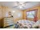Bedroom with wood-look wall paneling, ceiling fan, and a bed with a floral pattern comforter at 37812 Valencia Ave, Zephyrhills, FL 33541
