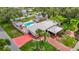 Stunning aerial view of single-story home featuring a large pool, carport, red driveway, and beautifully landscaped yard at 4002 Hudson Ter, Tampa, FL 33618