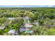 Aerial view showcasing home, lush surroundings, mature trees, a backyard pool, a detached garage, and colorful landscaping at 4002 Hudson Ter, Tampa, FL 33618