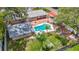 Aerial view of home showcasing a backyard pool, patio, lush landscaping, and a detached garage with a bright red driveway at 4002 Hudson Ter, Tampa, FL 33618