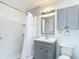 Cozy bathroom featuring gray vanity, shower with white tile, and built-in cabinet at 4002 Hudson Ter, Tampa, FL 33618