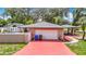 A detached garage with a gray shingle roof and a red painted driveway. Enhanced by manicured greenery and driveway pavers at 4002 Hudson Ter, Tampa, FL 33618