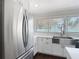 Stainless steel refrigerator with white cabinets and countertops in a bright kitchen with a large window at 4002 Hudson Ter, Tampa, FL 33618