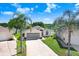Single-story home with well-manicured lawn and mature palm trees is situated next to a picturesque lake at 4407 Whitton Way, New Port Richey, FL 34653