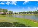 Scenic lake view surrounded by lush greenery and various residential buildings under a bright sky at 4407 Whitton Way, New Port Richey, FL 34653