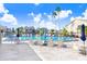 Community pool area with ample lounge chairs and tables under a clear blue sky with palm trees at 4407 Whitton Way, New Port Richey, FL 34653