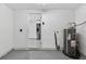 Utility area with water heater and view into kitchen area, concrete floor and white walls at 4535 15Th S Ave, St Petersburg, FL 33711