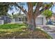 Frontal view of house featuring a stone facade, attached garage, and a mature tree enhancing its charm at 4535 15Th S Ave, St Petersburg, FL 33711