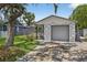 View of home featuring a stone accent, manicured lawn and driveway, and lush tree cover providing ample shade at 4535 15Th S Ave, St Petersburg, FL 33711