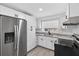 Bright kitchen featuring stainless steel refrigerator, white cabinets, and neutral granite countertops at 4535 15Th S Ave, St Petersburg, FL 33711