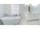 Bright bathroom with soaking tub, glass block window, and white marble accents at 5950 Bikini N Way, St Pete Beach, FL 33706
