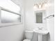 All-white bathroom with pedestal sink, toilet, window and modern lighting at 6220 Murdock Ave, Sarasota, FL 34231
