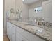Elegant bathroom featuring a double vanity with granite countertop and tiled shower with glass door at 6408 Seasound Dr, Apollo Beach, FL 33572