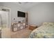 Bedroom with modern comforts including a TV, wooden storage, and a vibrant rug over wood-look tile floors at 6408 Seasound Dr, Apollo Beach, FL 33572