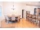 Open dining area with view to kitchen and bar, wood floors, and modern chandelier lighting at 6804 Pleasant Oaks Pl, Riverview, FL 33578