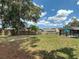 Wide open backyard with green grass, mature trees, and a wooden fence at 7511 Laurel Oak Ct, Port Richey, FL 34668