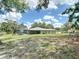 A large, green backyard view showcasing the home and the screened-in pool area at 7511 Laurel Oak Ct, Port Richey, FL 34668