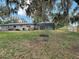 The backyard features a large grassy area, mature trees, and a screened-in pool at 7511 Laurel Oak Ct, Port Richey, FL 34668