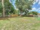 Large grassy backyard enclosed by a wooden fence and featuring mature trees at 7511 Laurel Oak Ct, Port Richey, FL 34668