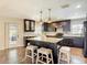 Modern kitchen featuring dark cabinetry, granite countertops, a center island with seating, and mosaic tile backsplash at 7511 Laurel Oak Ct, Port Richey, FL 34668