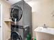 Modern laundry room with stacked washer and dryer, utility sink, and ample space for storage at 7511 Laurel Oak Ct, Port Richey, FL 34668