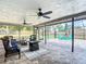 Inviting screened lanai featuring a fire pit, wicker furniture, ceiling fans and relaxing views at 7511 Laurel Oak Ct, Port Richey, FL 34668