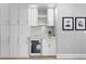 Custom bar area with white cabinets, gold hardware, wine fridge, and decorative backsplash at 10003 Brompton Dr, Tampa, FL 33626