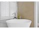Bright bathroom featuring a freestanding tub, shuttered window, and gold fixtures at 10003 Brompton Dr, Tampa, FL 33626