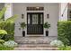 Elegant front entrance with a stylish black door, potted plants, and stone steps at 10003 Brompton Dr, Tampa, FL 33626