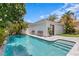 Outdoor pool with blue tile and patio area, complemented by benches, lush landscaping, and white exterior at 10003 Brompton Dr, Tampa, FL 33626