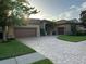 Beautiful exterior elevation showcasing a manicured front yard with a paver driveway, and a three-car garage at 1008 Arista Blvd, Valrico, FL 33594