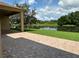 Covered brick patio overlooks a serene pond, offering a perfect outdoor retreat at 1008 Arista Blvd, Valrico, FL 33594