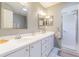 Bright bathroom with a double vanity, white cabinets, and a shower with a glass door at 10728 Moshie Ln, San Antonio, FL 33576