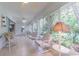 Bright sunroom with tile floors, comfortable seating, and large windows overlooking a lush backyard at 10728 Moshie Ln, San Antonio, FL 33576