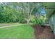 Spacious yard with mature trees and lush landscaping, leading to a charming home at 10728 Moshie Ln, San Antonio, FL 33576