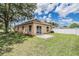View of the home's backyard, showcasing a green lawn, small concrete patio, and a sliding glass door entrance at 11022 Connacht Way, Tampa, FL 33610