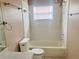 Clean bathroom featuring a bathtub with shower, a toilet, and a window for natural light, designed for comfort at 11022 Connacht Way, Tampa, FL 33610