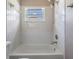 Bright bathroom featuring a white tiled shower-tub combination and window at 11022 Connacht Way, Tampa, FL 33610