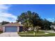 Charming single-story home with a well-manicured lawn, mature trees, and a blue painted two-car garage door at 11022 Connacht Way, Tampa, FL 33610